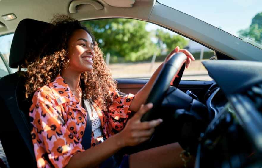 Woman driving and smiling behind the wheel